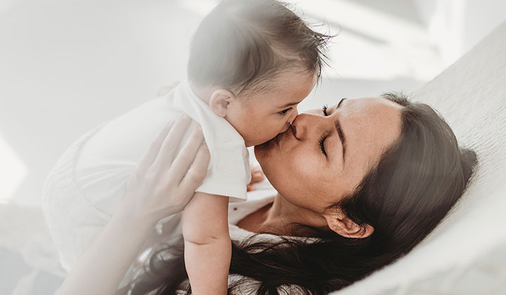 mother kissing infant