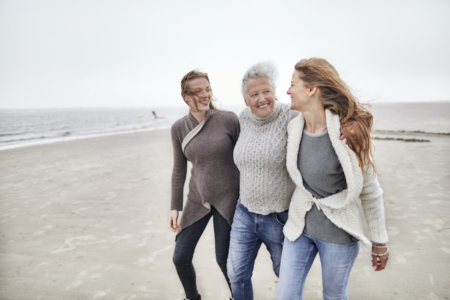 3 women of varying age walking on the beach