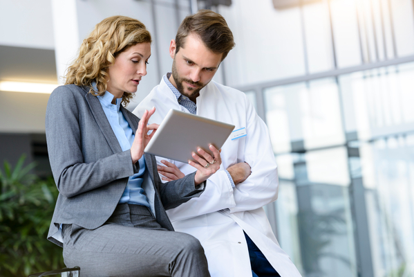 Two medical professionals talking while looking at tablet