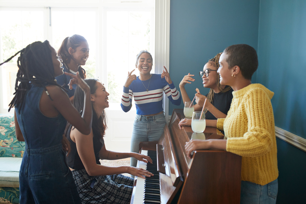 Cheerful friends dancing while enjoying music on piano at home