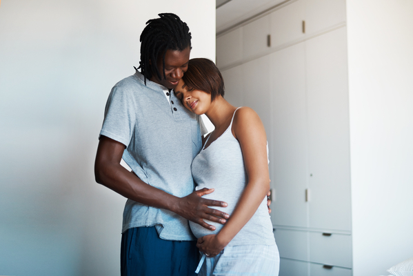 Shot of happy young man posing with his pregnant wife at home