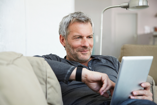 Portrait of man sitting on couch and working on tablet PC
