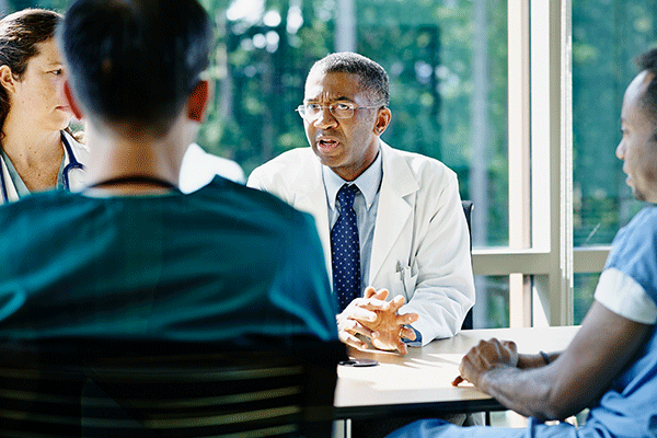 Mature male doctor leading discussion in medical team meeting in conference room in hospital