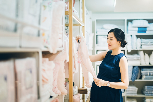 Smiling young pregnant woman shopping for baby clothes in shop